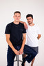 Two men standing next to each other wearing MANON t-shirts.